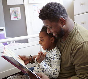 Un homme lit un livre à un enfant à l'heure du coucher.